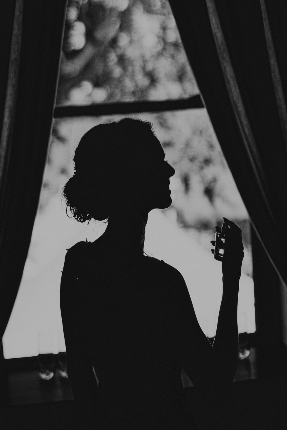 Dramatic silhouette of figure against window with dreamy bokeh background.