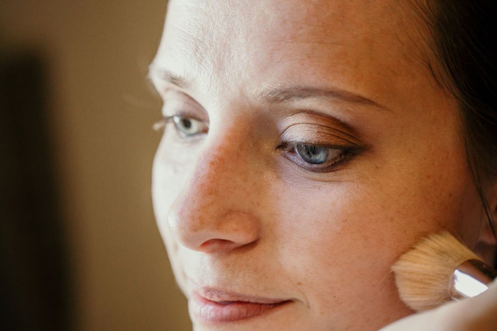 A makeup brush applies powder during bridal beauty preparation.