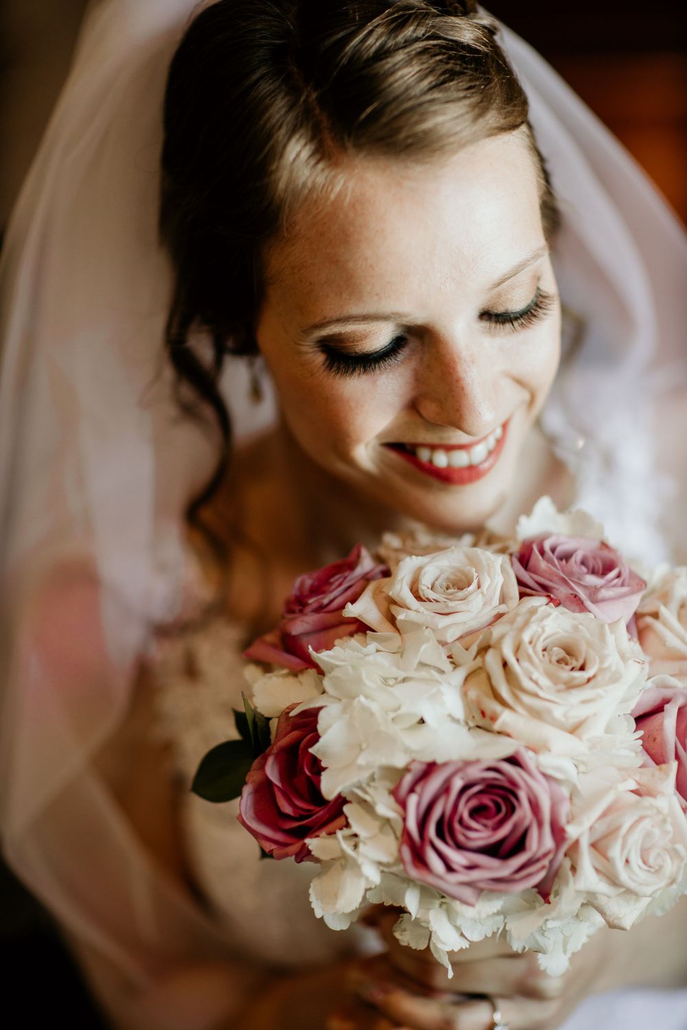 Close-up shot of bridal bouquet with pink and white roses against soft background.
