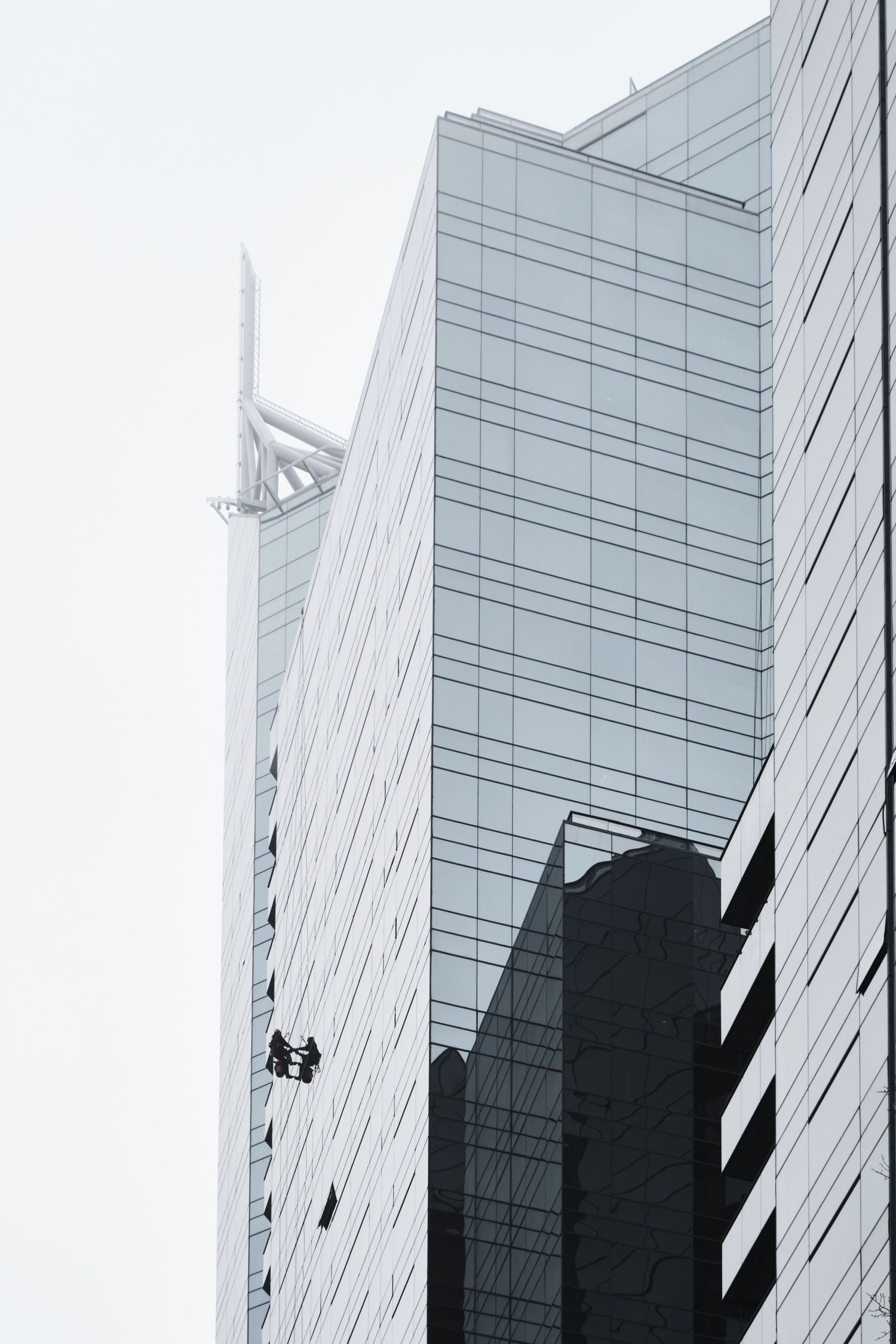 Modern glass office buildings with diagonal lines and strong shadows create a striking architectural composition.