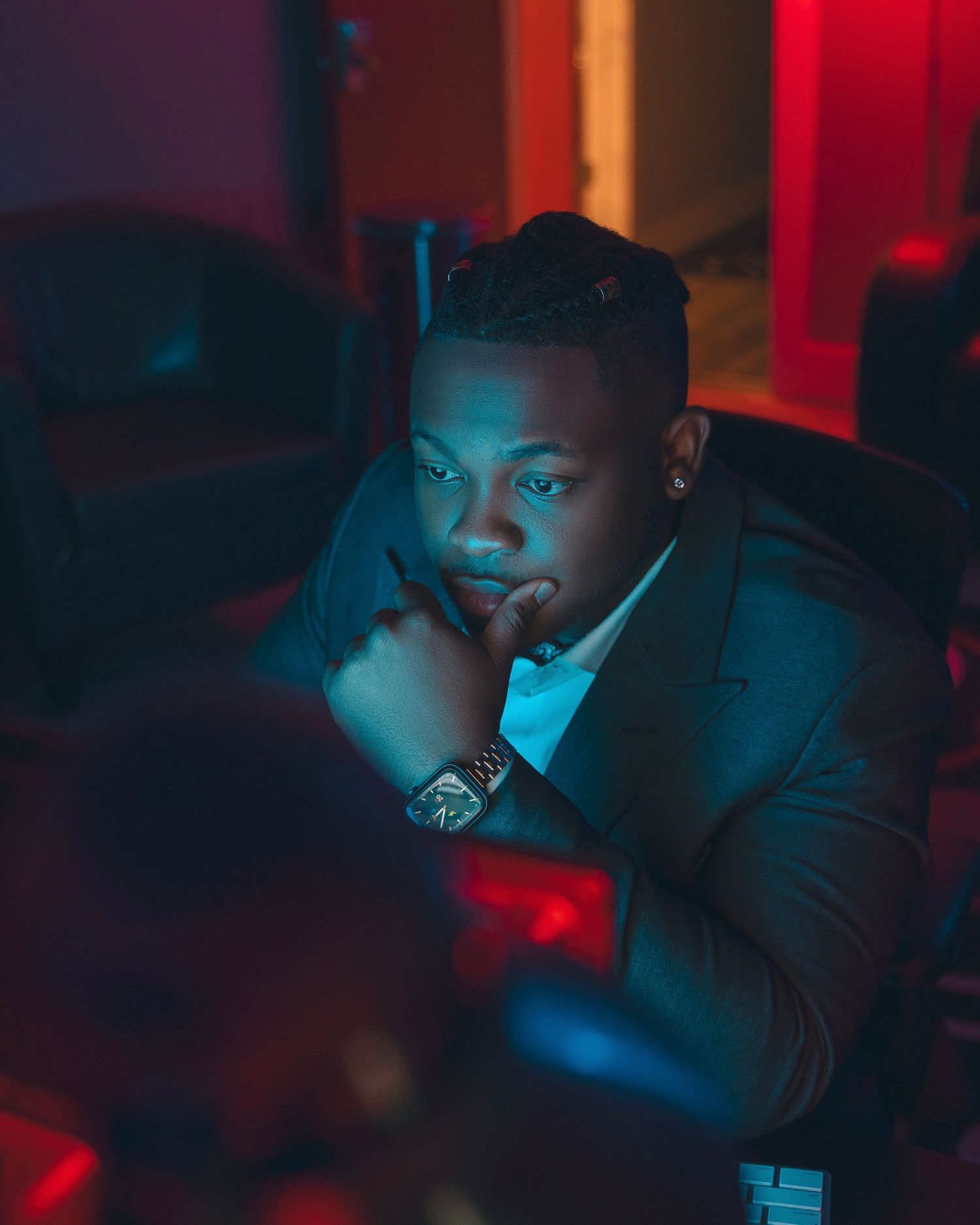 A moody portrait with blue and red lighting shows a person in formal attire.