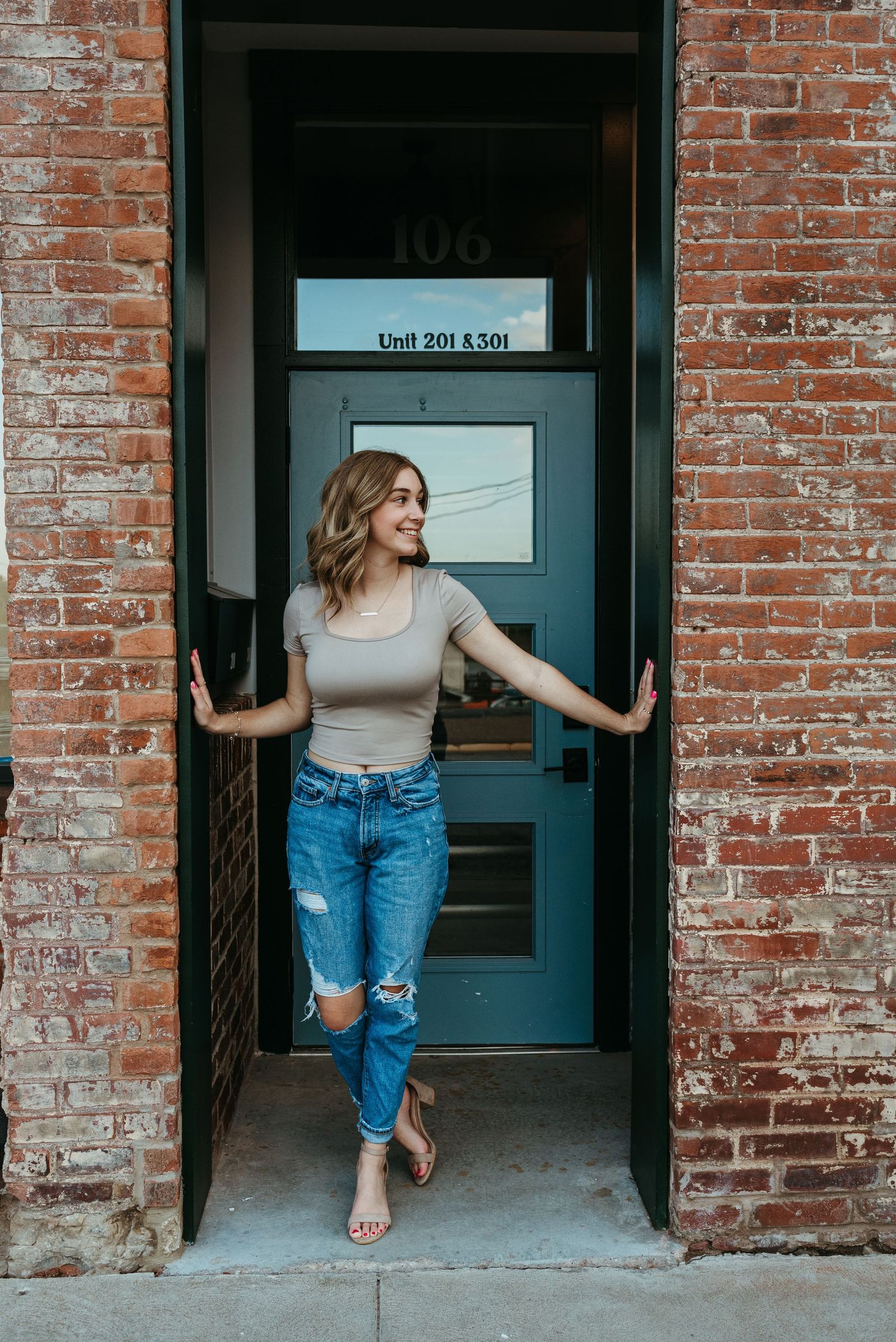 Casual portrait of person posing in doorway of brick building with blue door.