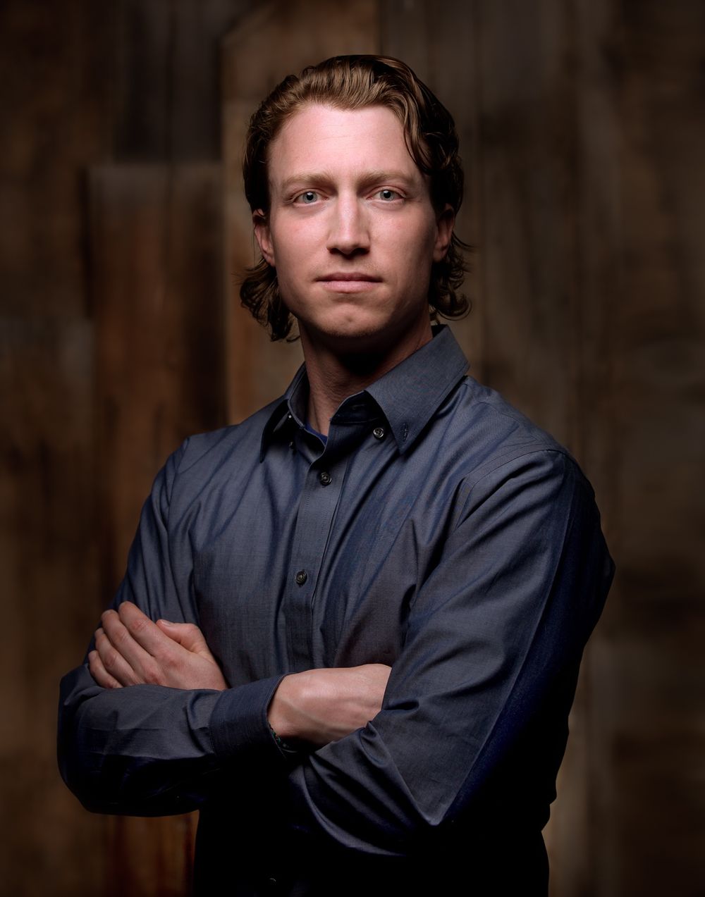 Studio portraits against dark wood paneling with dramatic side lighting.