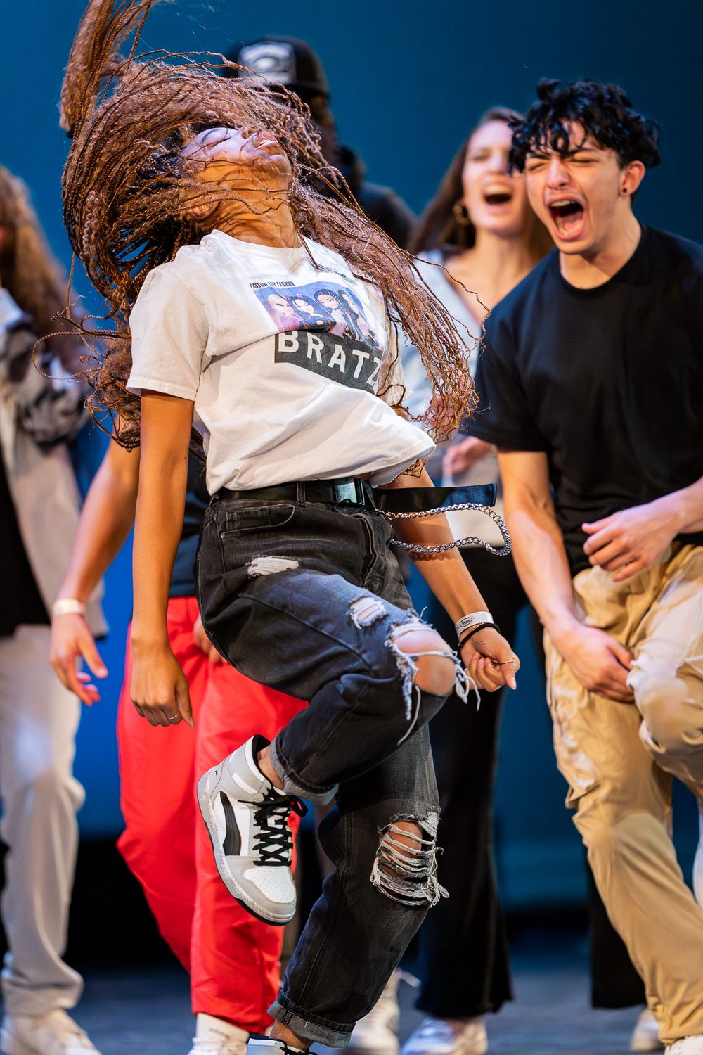 Energetic dancer with flying hair performs dynamic street dance move on stage.