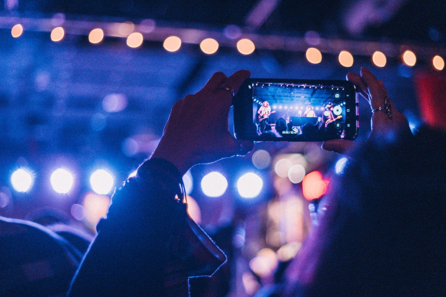 close up of a person's phone while they are recording a video of the performance on stage.