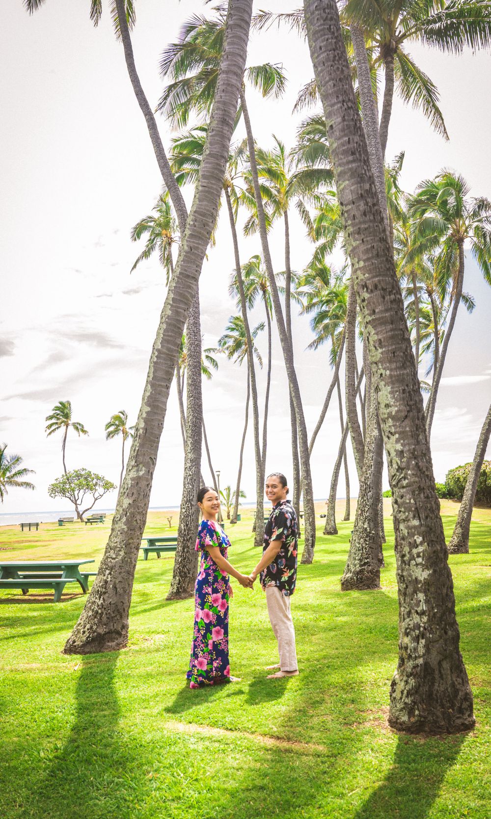 A couple enjoys a romantic stroll through a majestic palm tree grove in Hawaii.