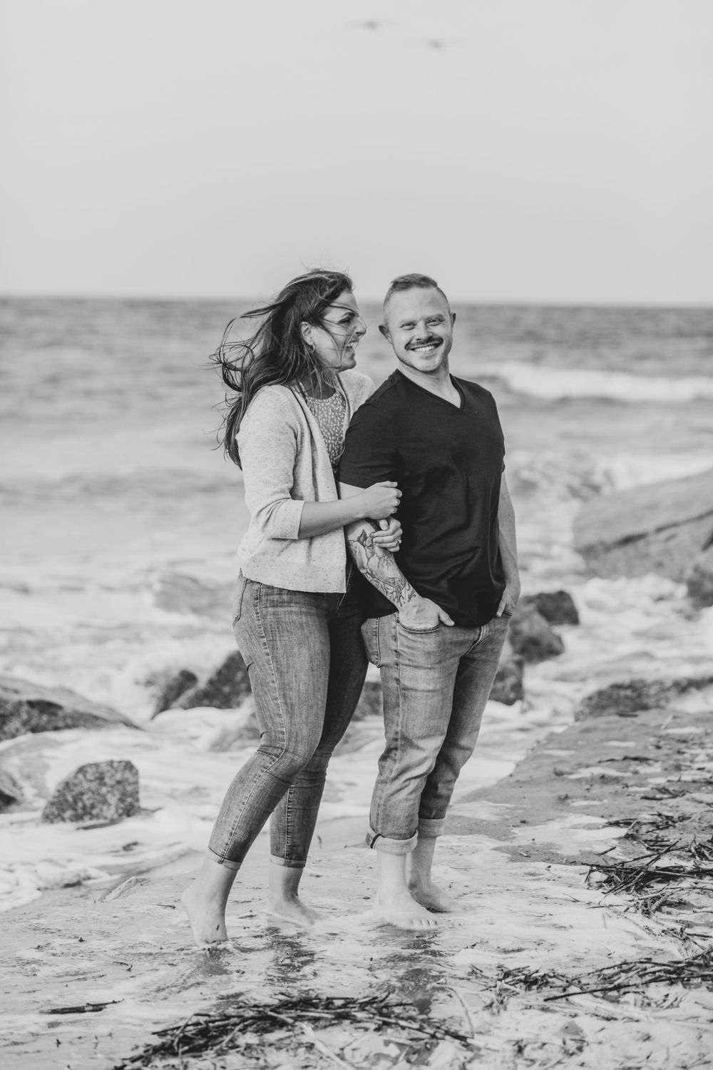 Couple enjoying intimate moments together on a rocky beach shoreline.