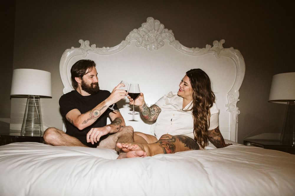 Romantic couple relaxing on white bed with champagne glasses.