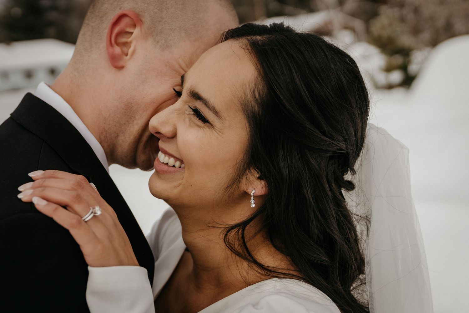 Intimate wedding photo of couple sharing a joyful moment in the snow.