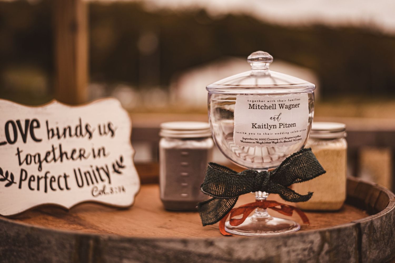 Wedding decorations and mason jars displayed on wooden surface with romantic message sign.