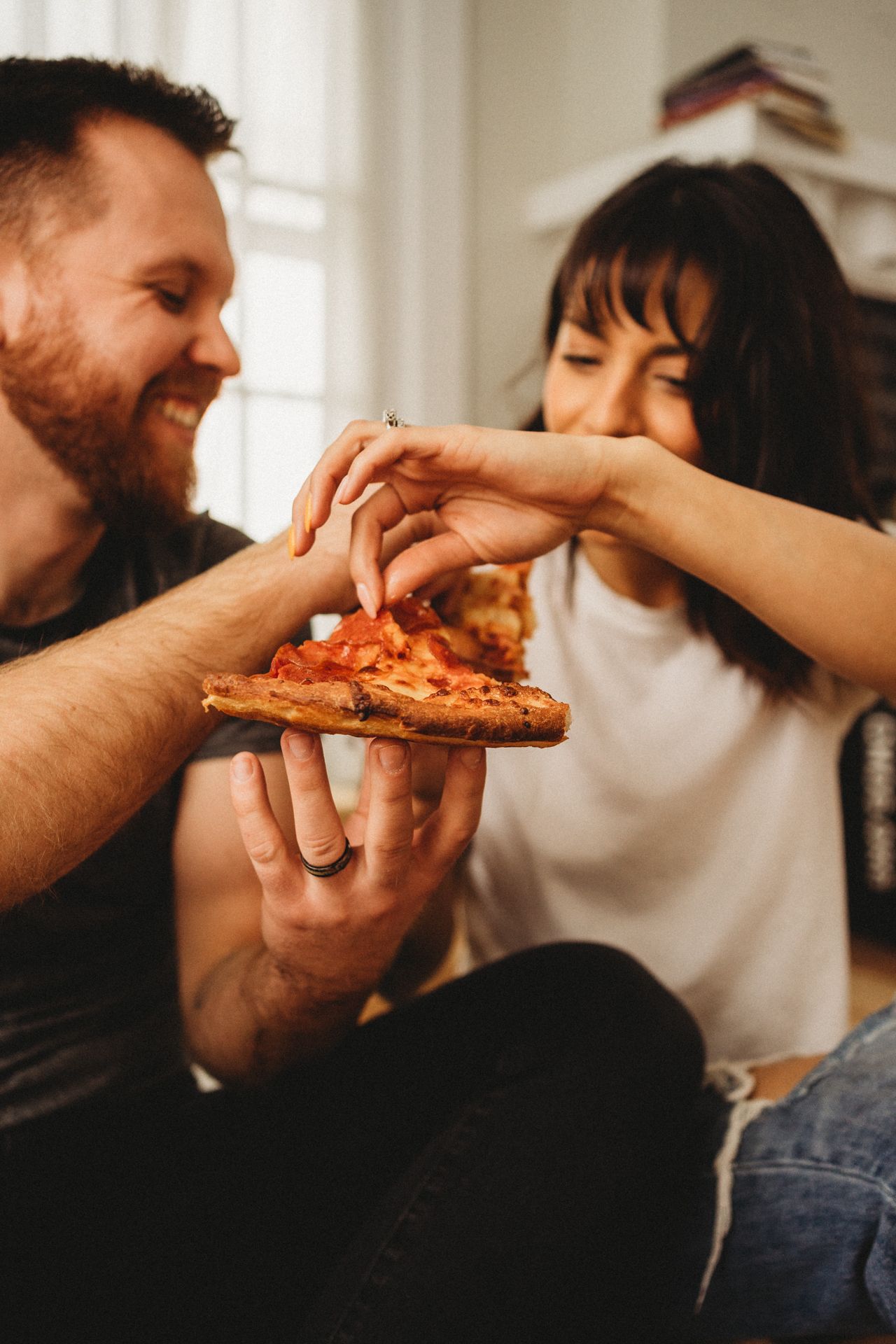 Close up of hands sharing stretchy cheese pizza slice.