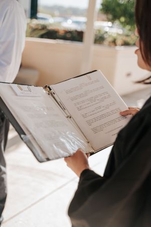 A close-up of hands holding an open binder with document pages visible.