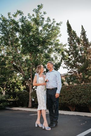 Full length portrait of couple in garden setting with trees.