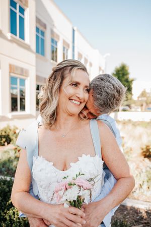 Romantic outdoor portrait with white building and garden in background.