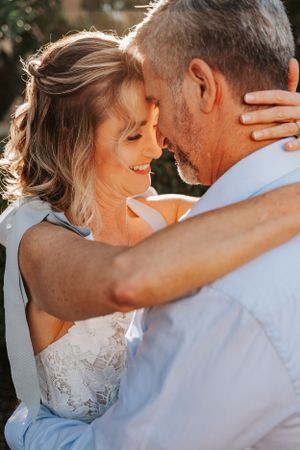 Intimate outdoor wedding portrait with golden hour lighting and natural smiles.