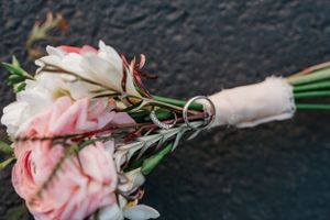 Pink roses wrapped in white paper laying on a dark textured surface.