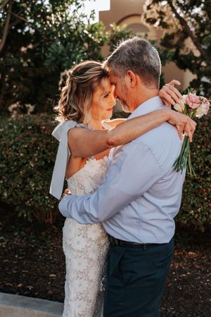 Romantic sunset wedding portrait with lace dress and pink bouquet.