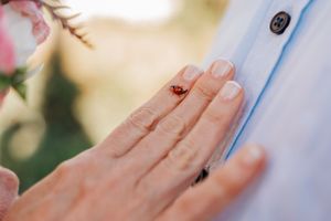 Close-up of wedding ring on hand against white fabric.