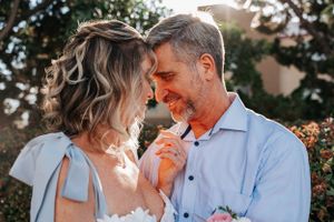Candid wedding moment with pink flowers against outdoor garden setting.