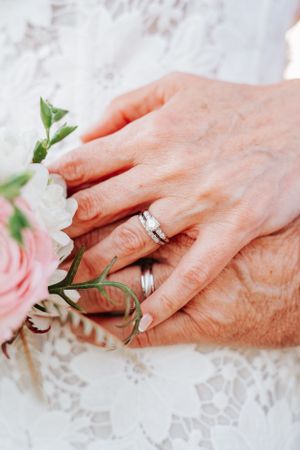 Detail shot of wedding rings with pink roses and white lace.