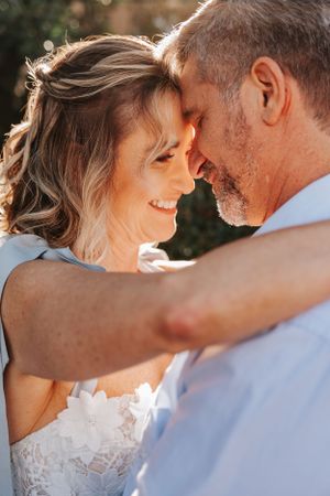 Romantic couple shares an intimate moment outdoors with sunlit bokeh background.