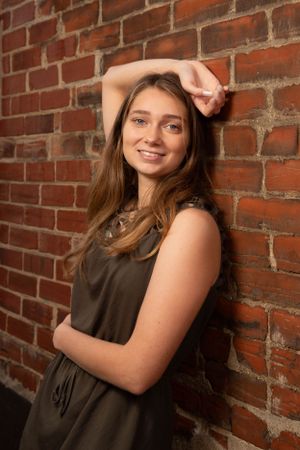 senior girl portrait close up leaning against brick wall