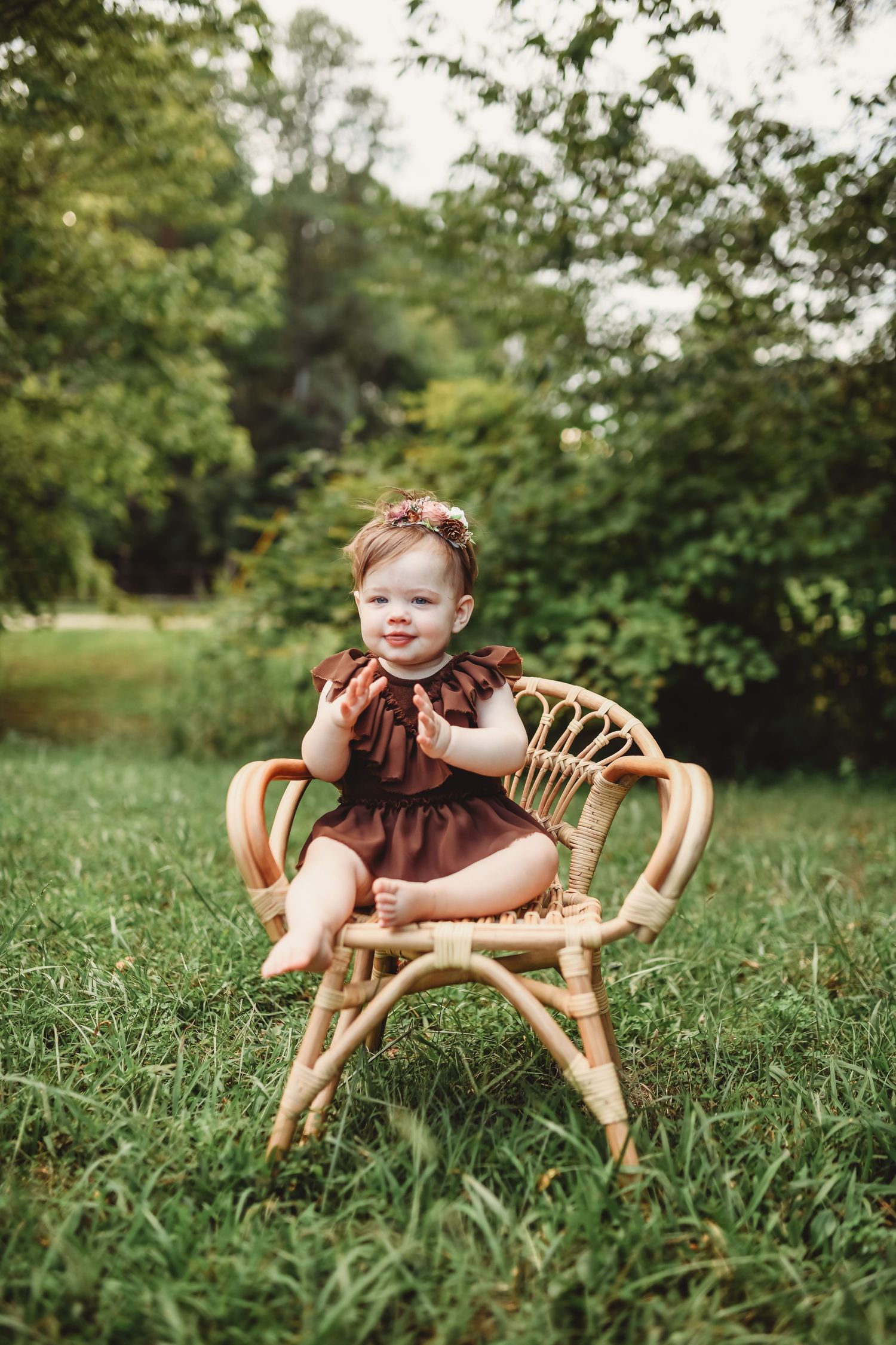 Vintage wicker chair sits in lush green grass during outdoor photo session.