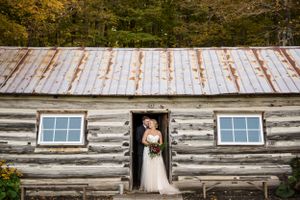 Bride and groom standing in a doorway of a cottage-like building