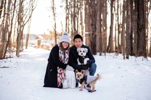 A young couple crouching down with their two dogs in a winter forest