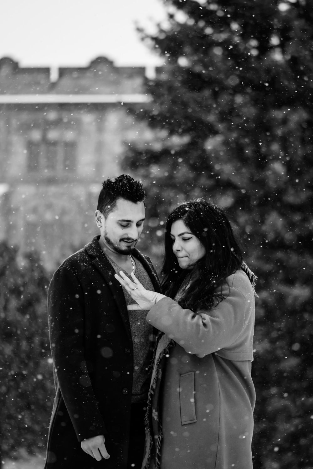 A young woman admiring her new engagement ring beside her fiance