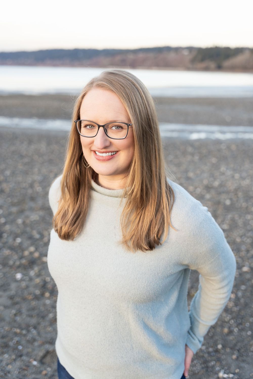Beachside portrait in cream sweater with coastal background.