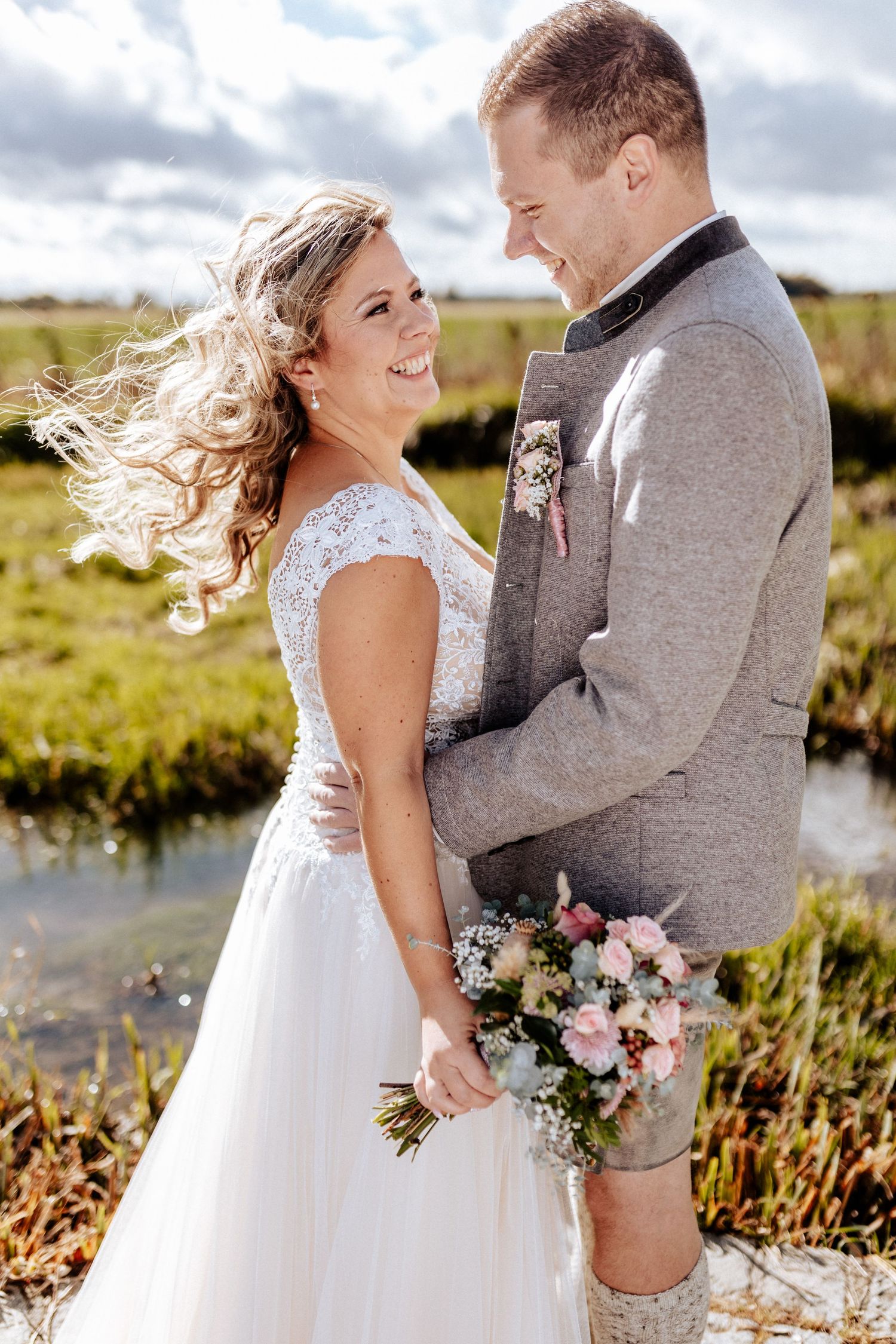 Wind-swept wedding portrait with natural light and pink bouquet.