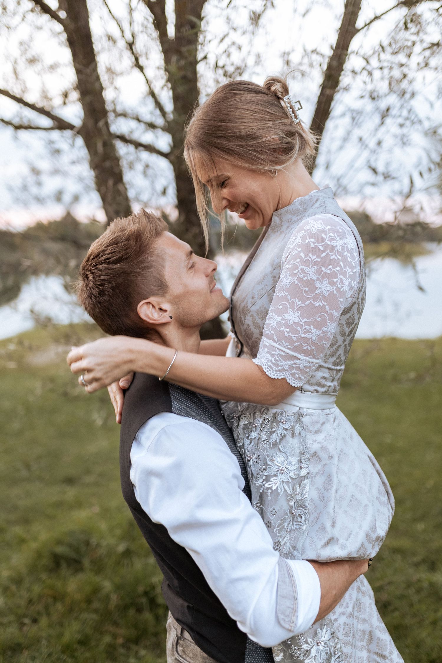 Romantic moment captured between couple in traditional Bavarian dress by the lake.