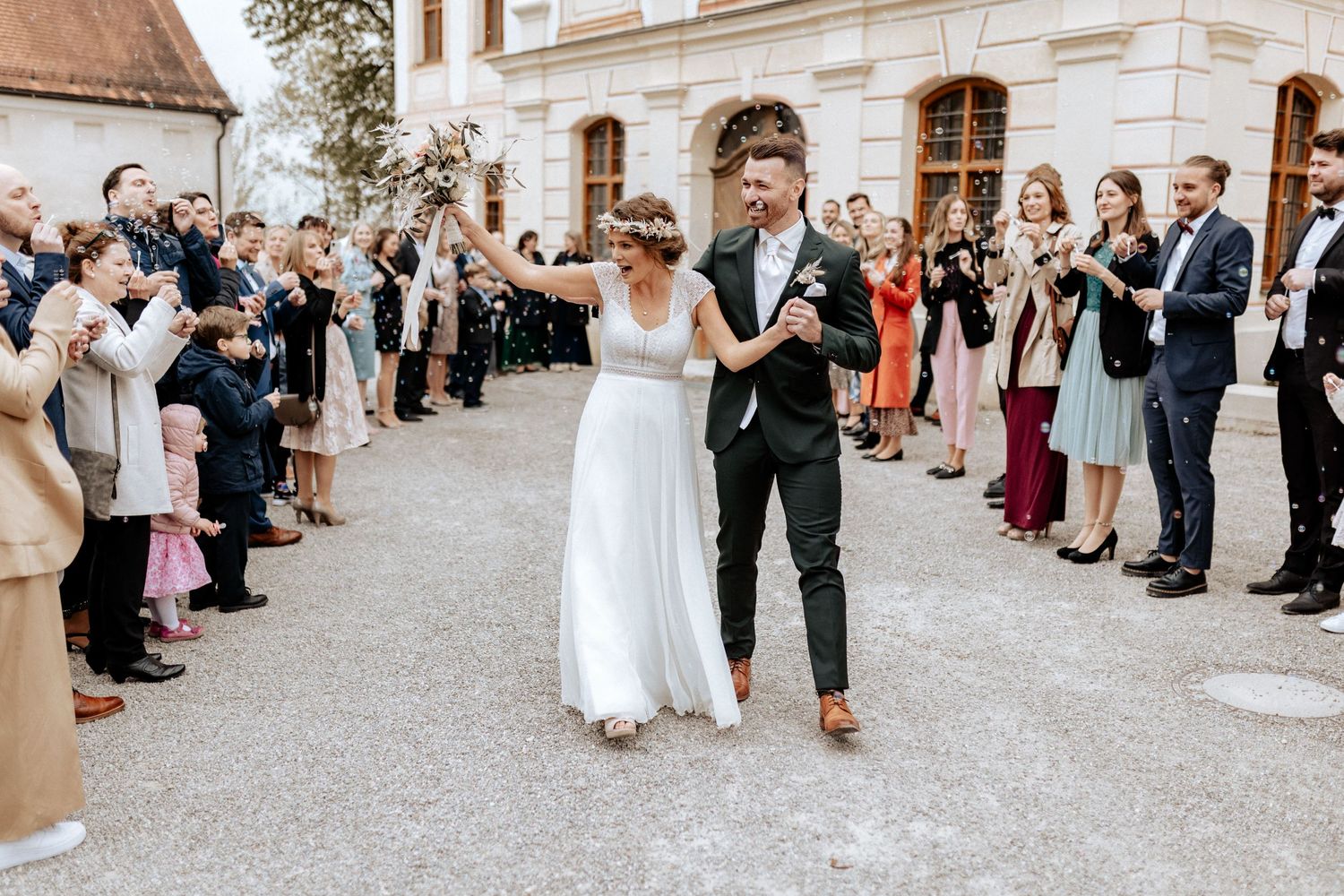 Wedding couple exiting venue while guests line pathway clapping and celebrating.