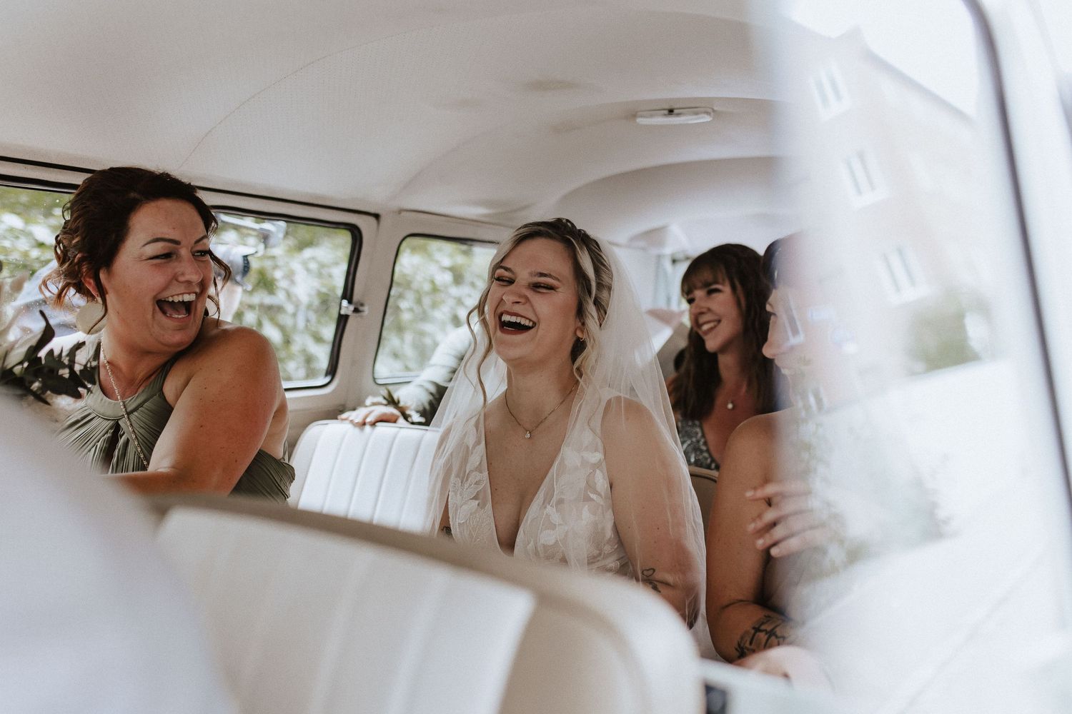 Happy wedding party sharing laughs inside vintage vehicle.