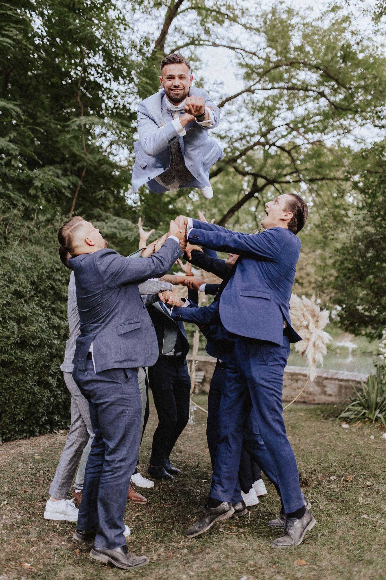 Groomsmen performing a fun group photo stunt by throwing one member into the air.
