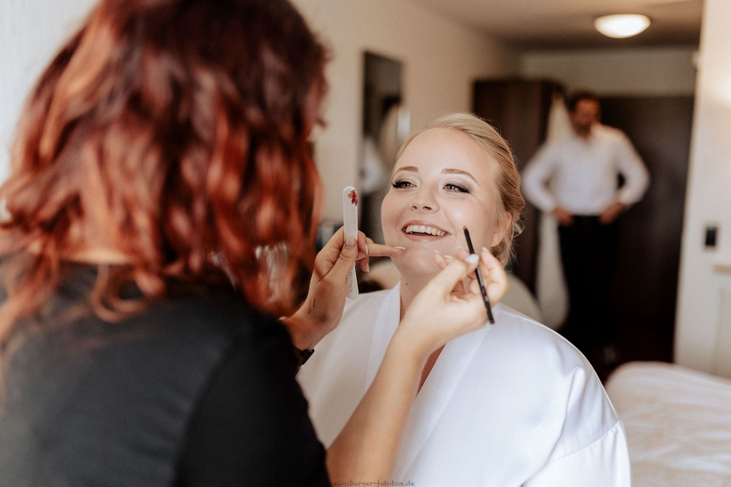 Wedding preparation scene with makeup application in morning light.