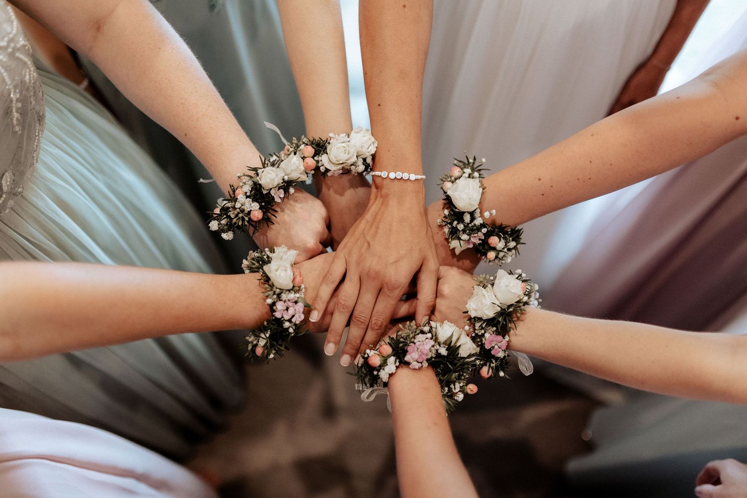 Hands adorned with delicate floral corsages join together in a circle.