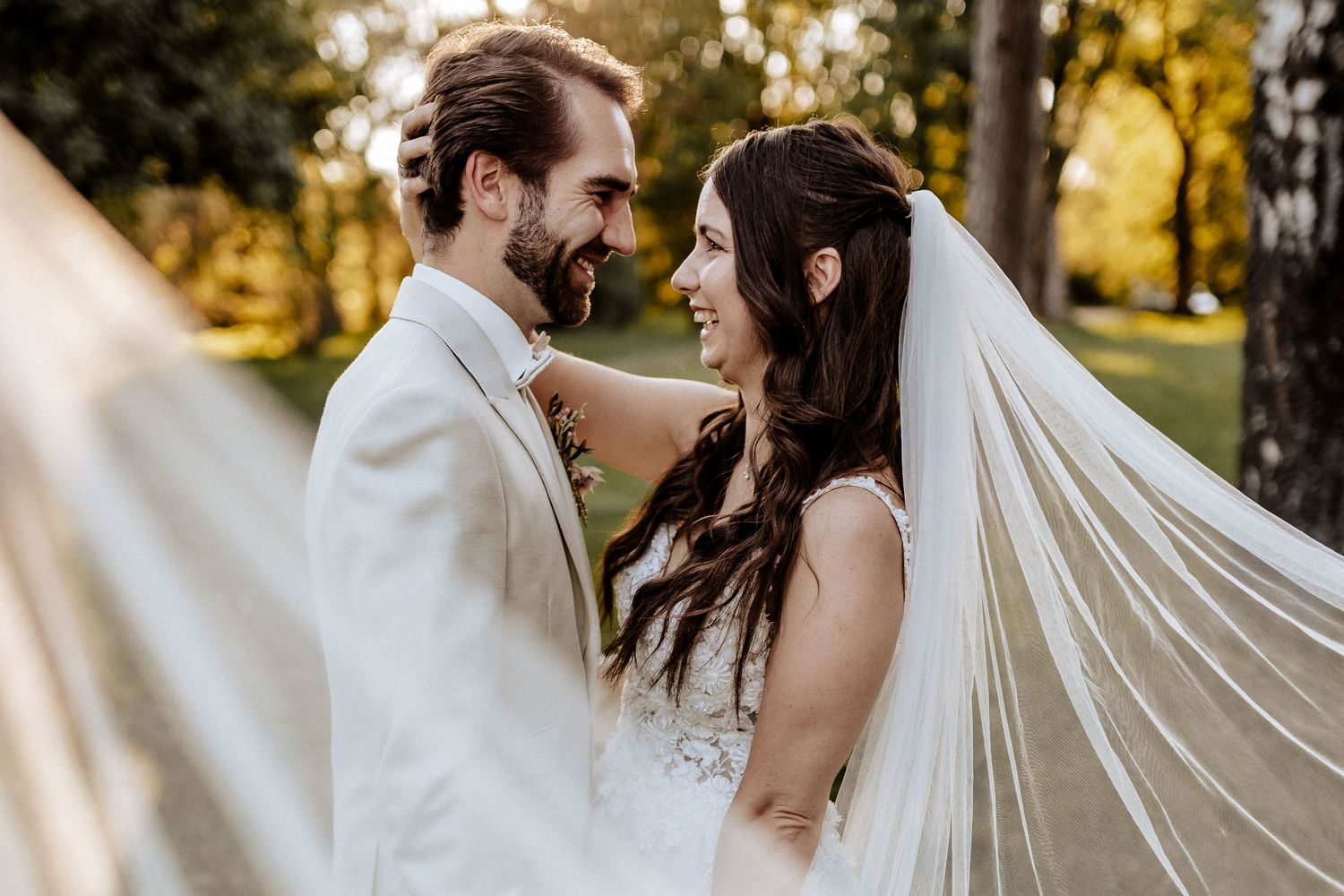 Intimate wedding portrait with flowing veil during golden hour.