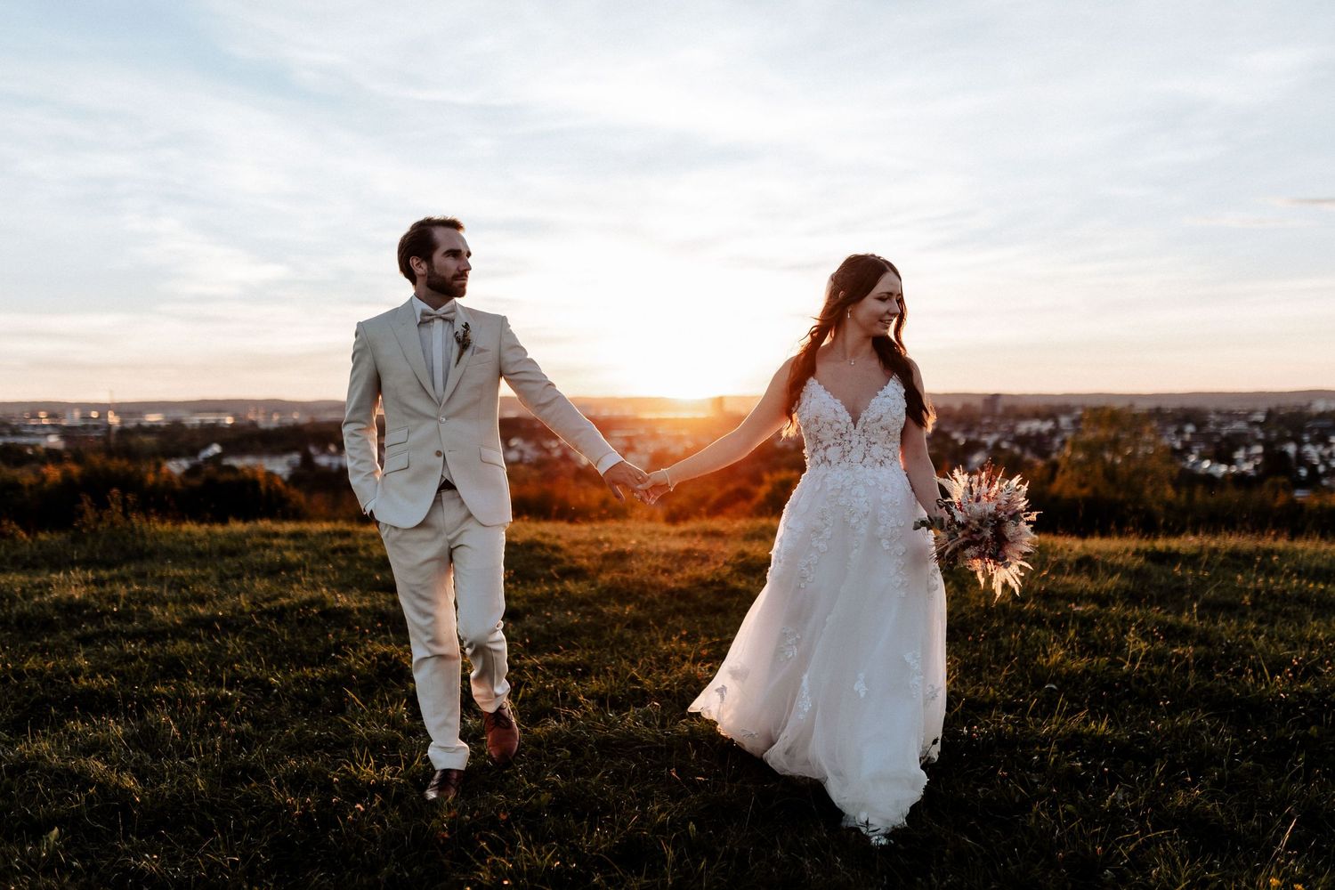 Couple runs through field during golden hour wedding photoshoot.