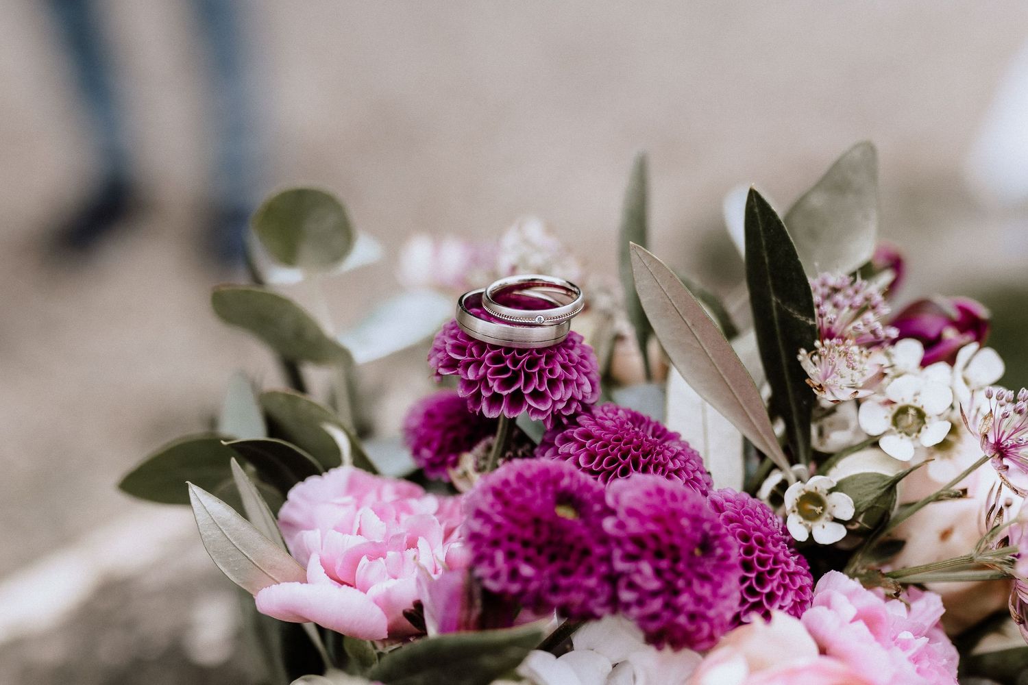 Close-up of wedding rings with pink and purple floral arrangement.