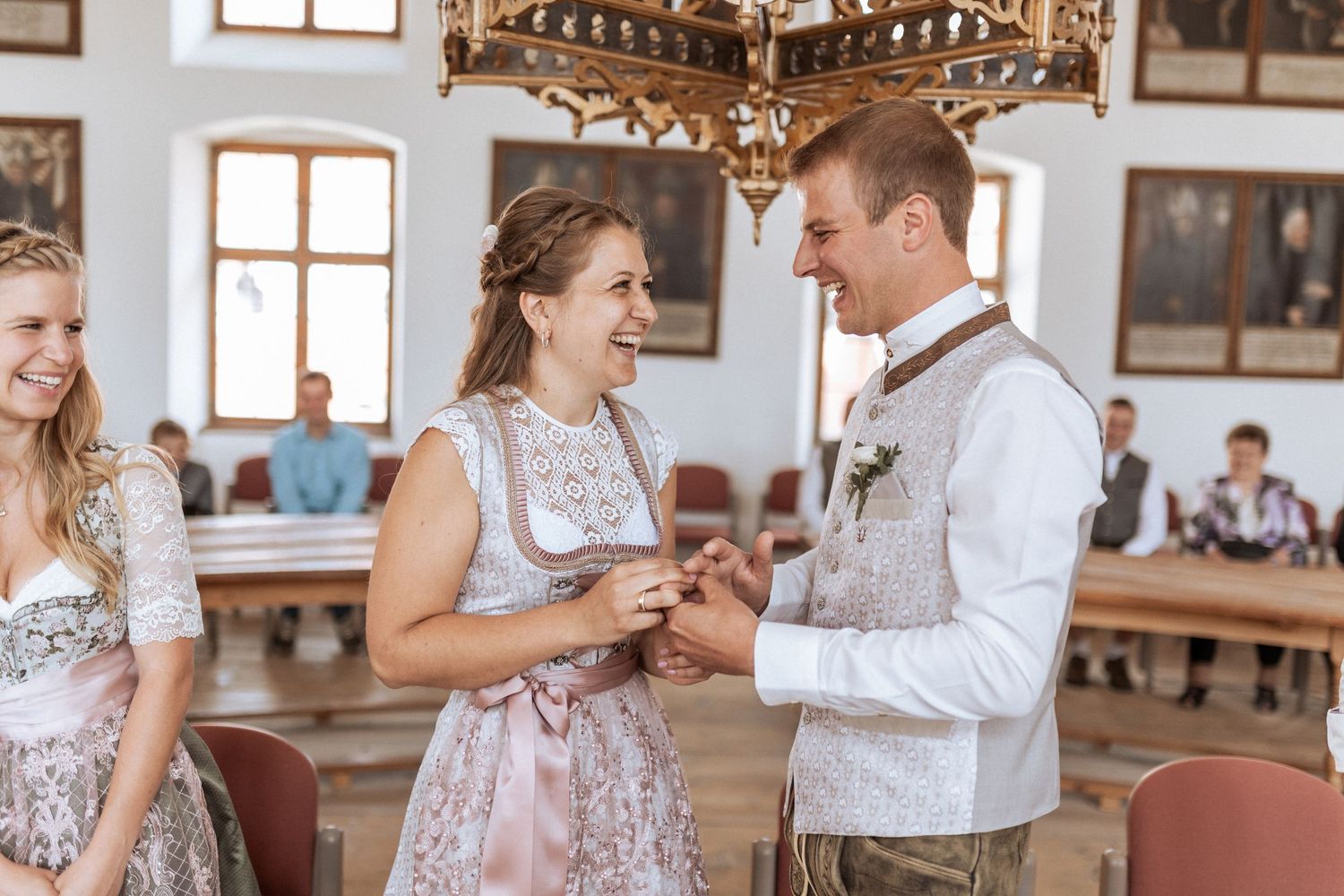 Traditional wedding ceremony taking place in an elegant historic room with a chandelier.