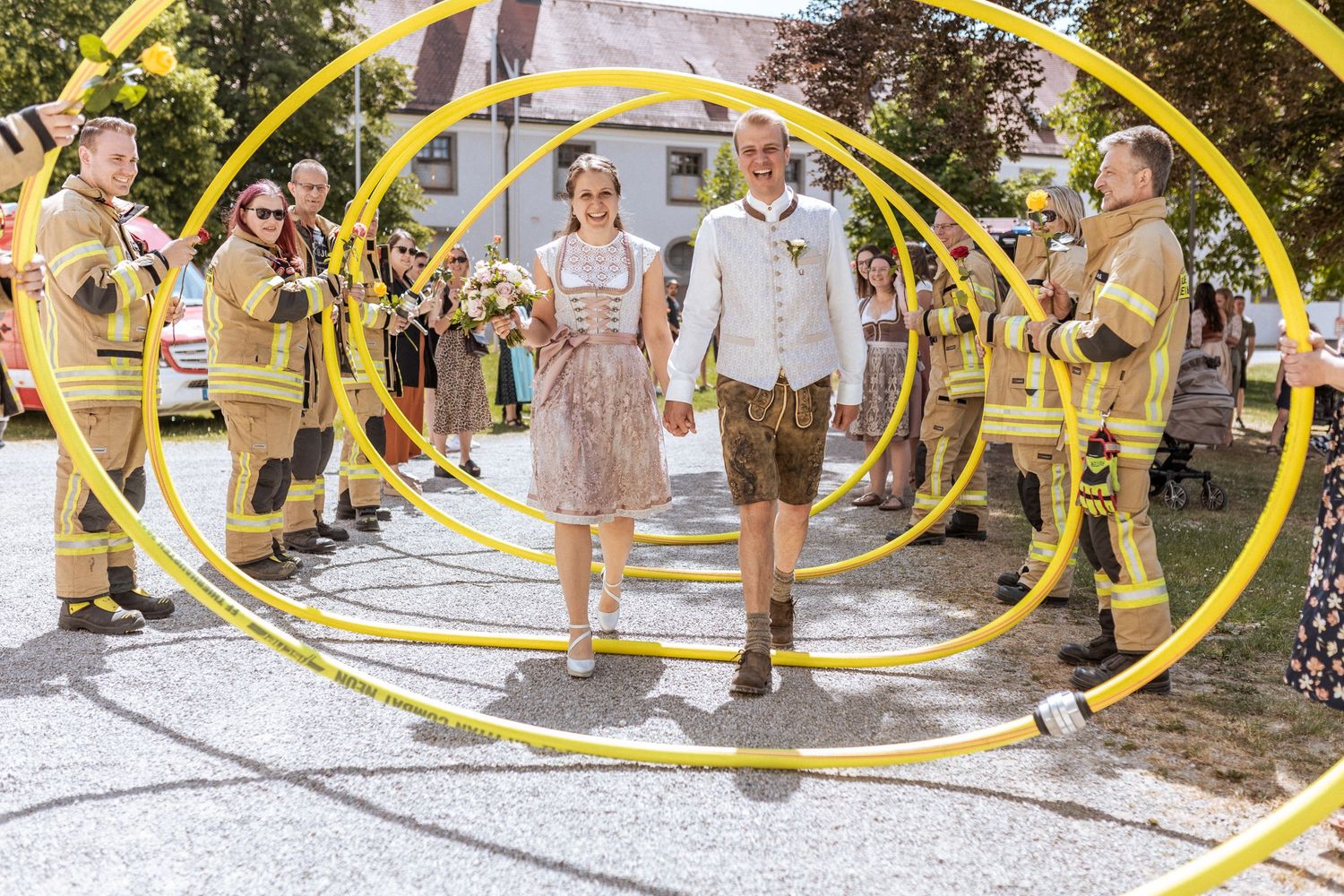 Wedding couple walking through yellow hoop arches with guests in outdoor celebration.