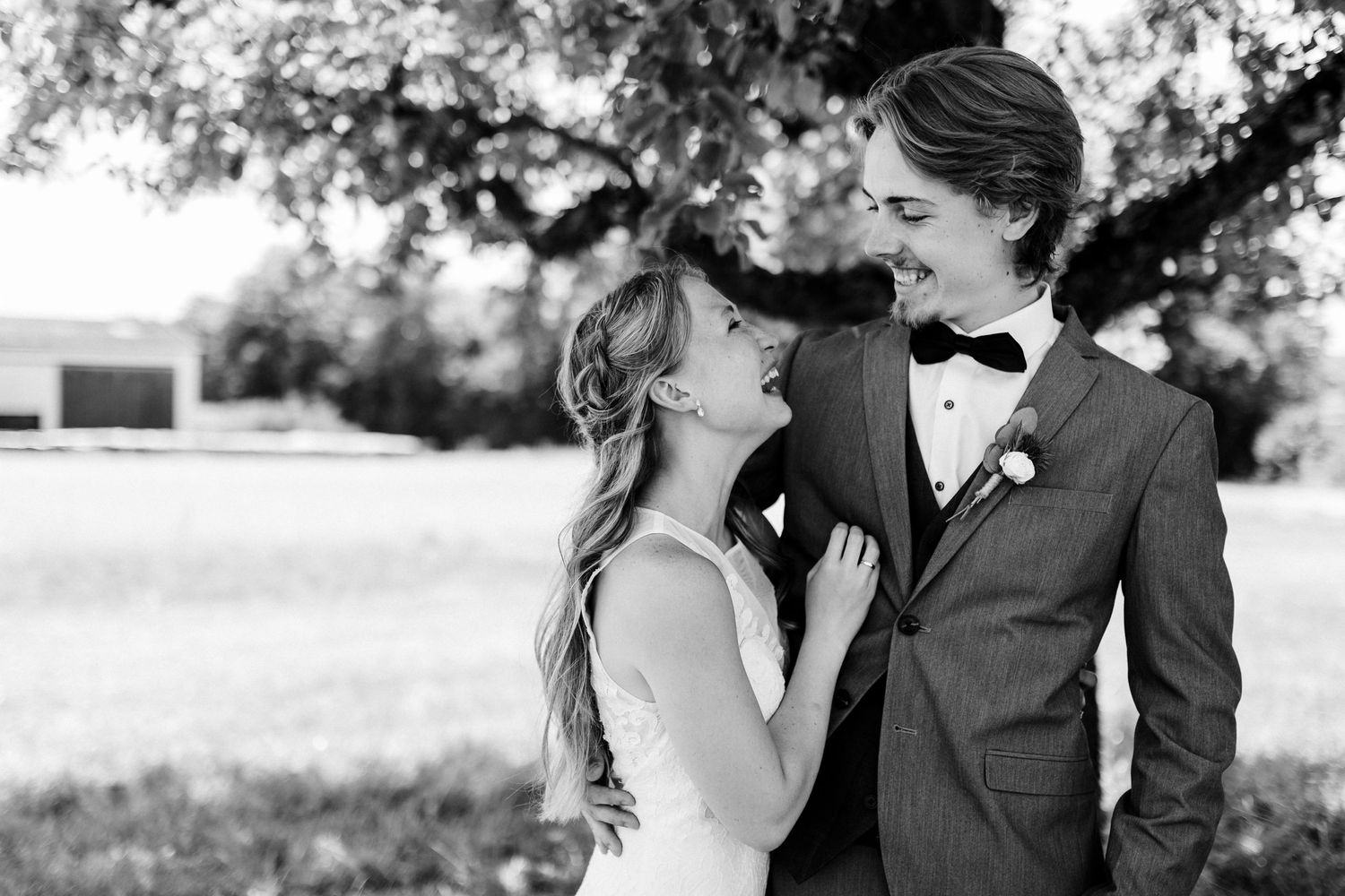 Black and white portrait of a couple sharing a tender moment outdoors on their wedding day.