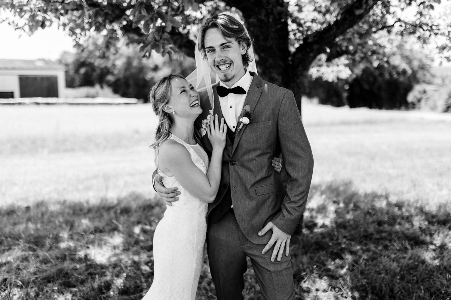 A black and white wedding portrait showing a tender moment under a tree.