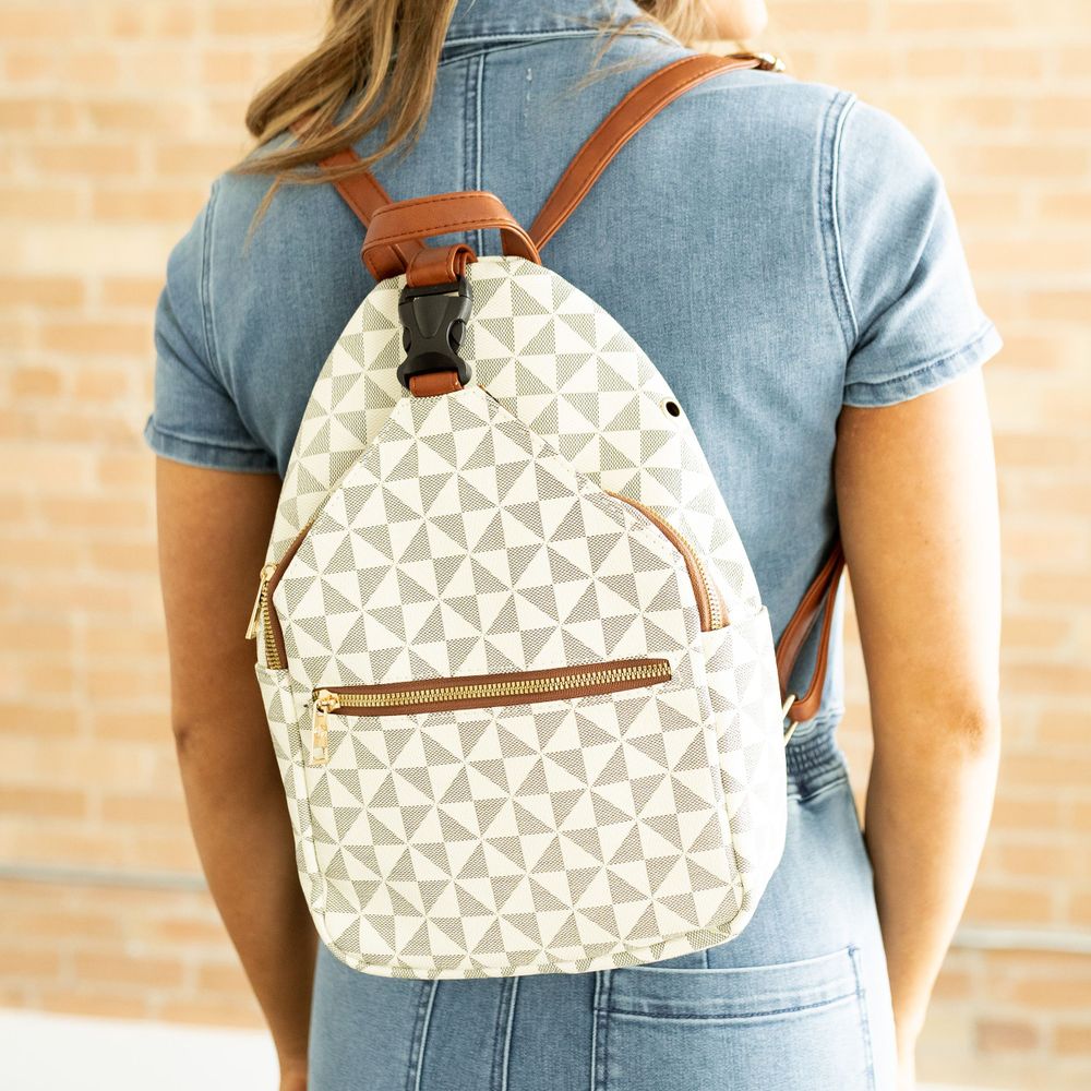 A cream and tan geometric patterned backpack with leather trim worn with denim.
