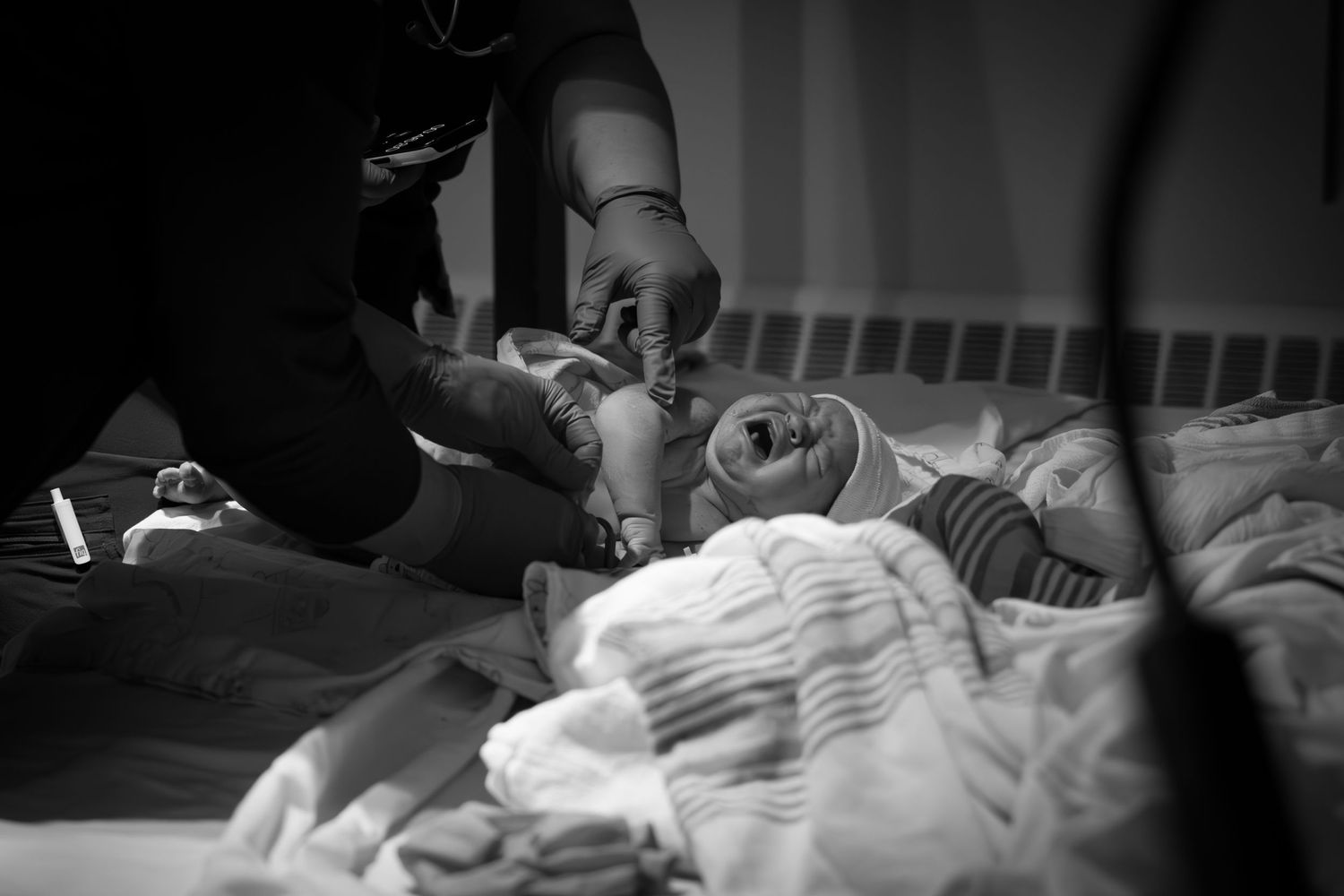 Black and white photo of a newborn baby being examined by a healthcare provider.