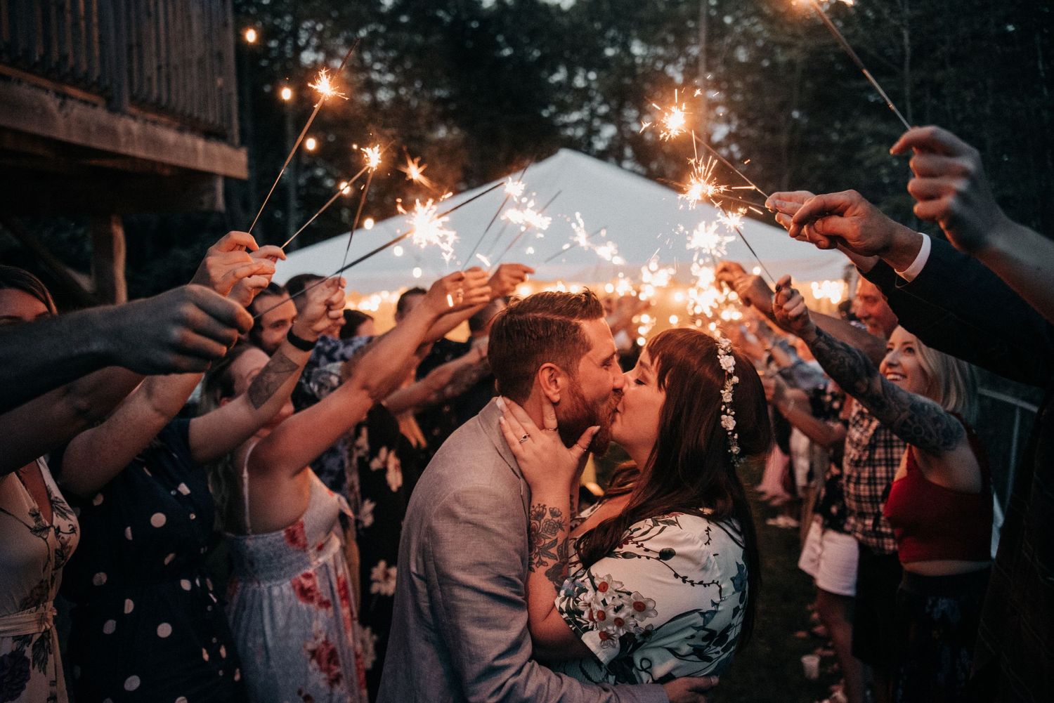 Wedding guests holding sparklers create a magical tunnel of light around the celebrating couple.