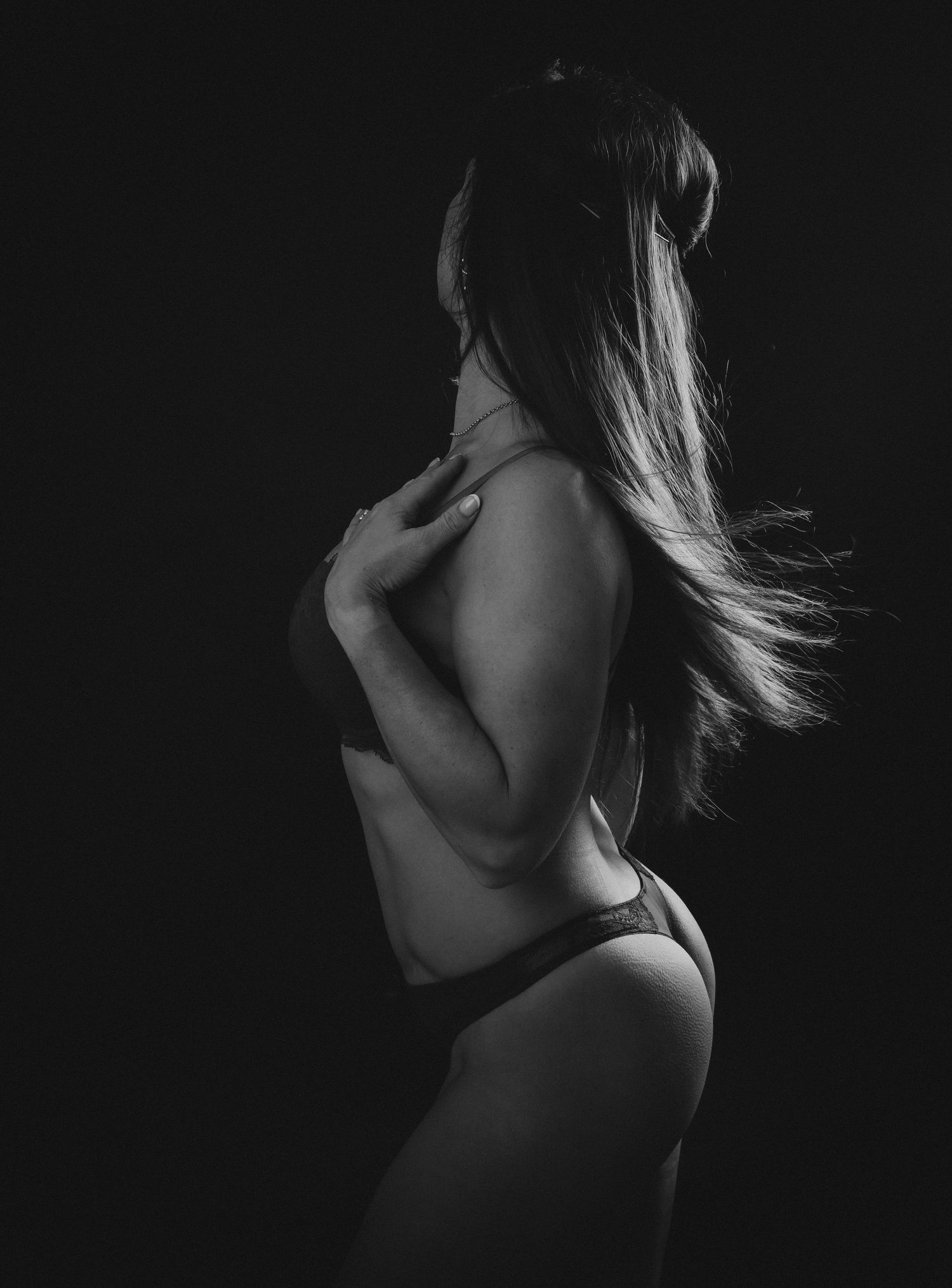 Artistic nude silhouette showcasing feminine curves against dark background.