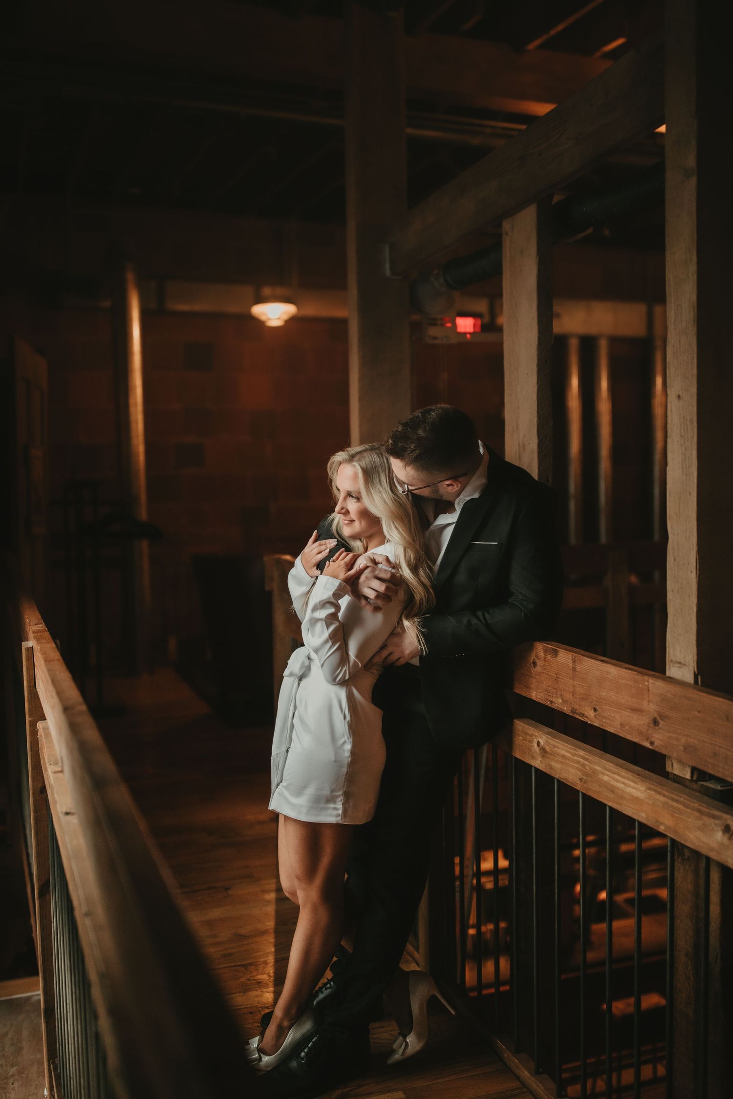 Intimate couple portrait in dimly lit rustic wooden interior.